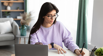 Female student sitting at her desk at home working on her homework.